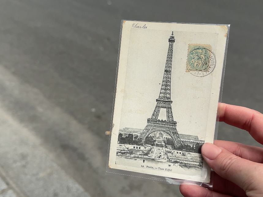 A person presents a postcard of the Eiffel Tower, showcasing the iconic landmark.