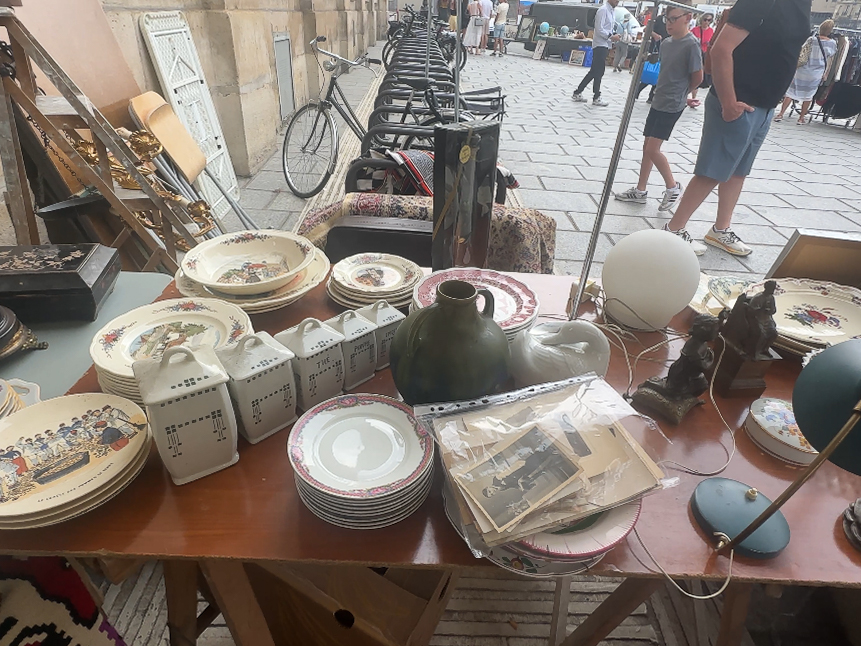 A table filled with an assortment of items, such as dishes, tools, and personal belongings.