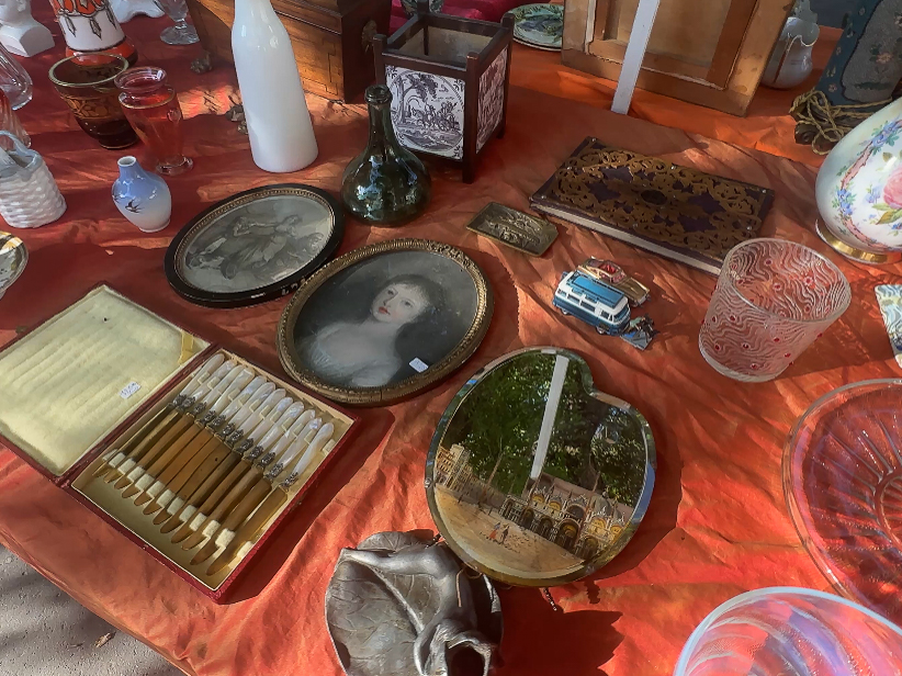 A variety of antiques and collectibles displayed for sale at a bustling flea market.