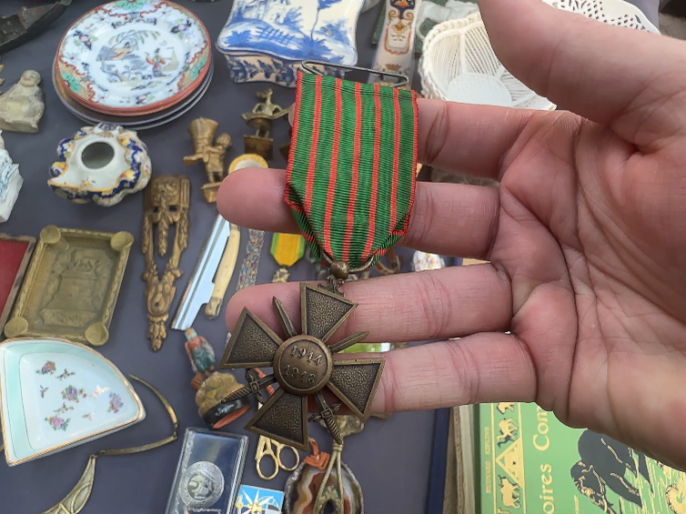 A person showcases a medal adorned with a ribbon and a cross, signifying a notable achievement or award.