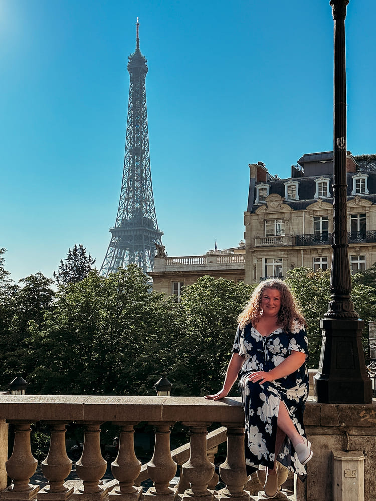 A woman takes a memory picture with the Eiffel Tower.