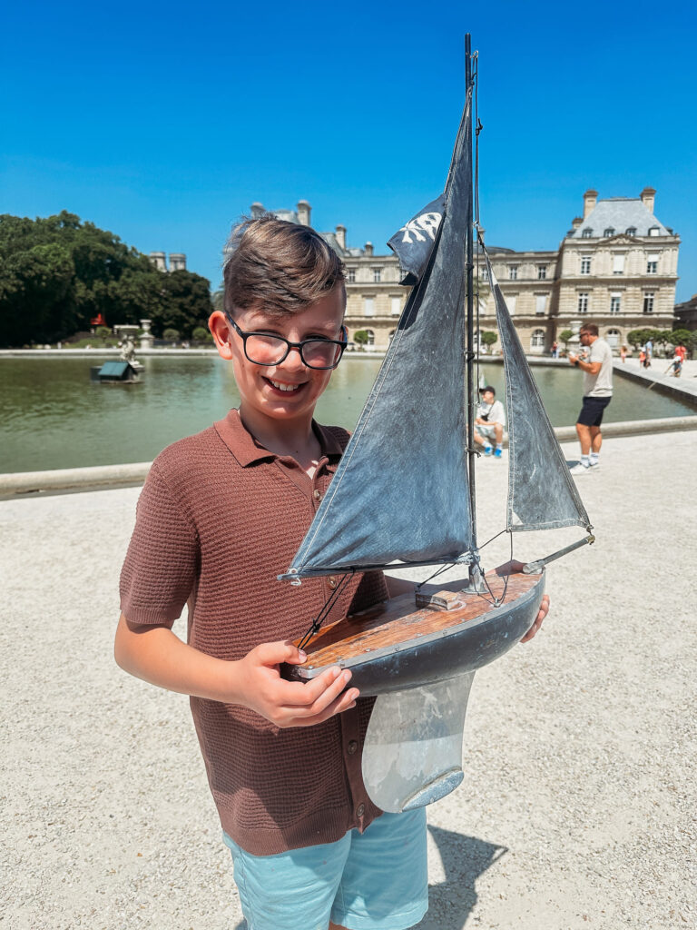 The boy is holding a small sailboat he rented.