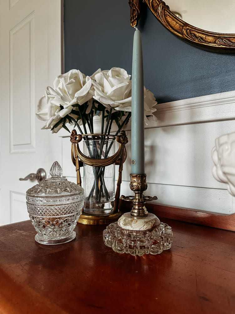 A tabletop scene featuring a mirror, a flickering candle, and a stylish vase, enhancing the room's decor.
