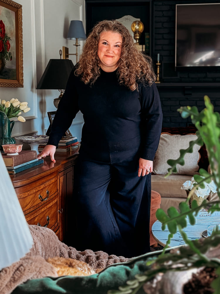 woman standing in a living room by a vintage console and thrifted vintage home decor